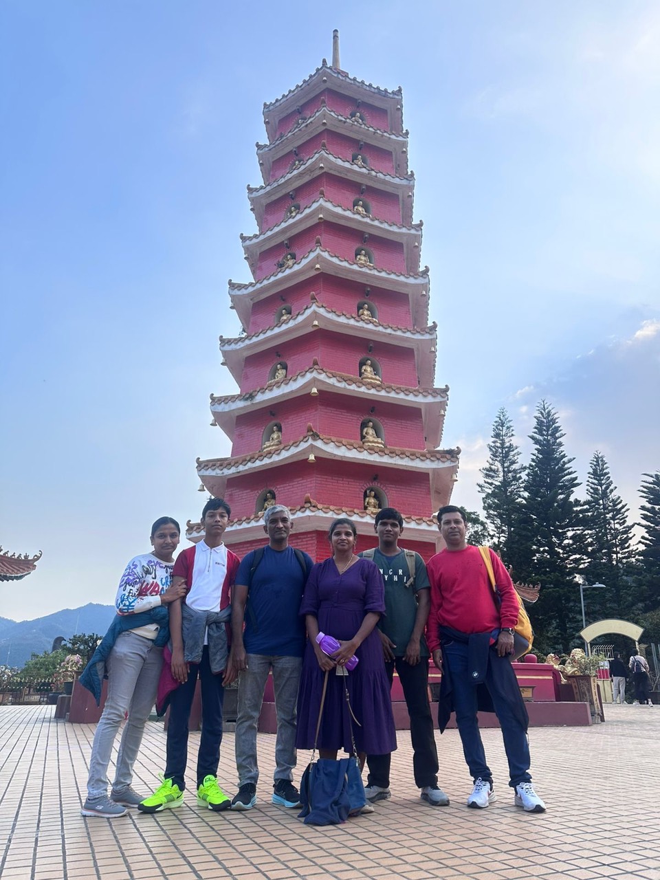 A group of travellers gathered in front of a tall pagoda