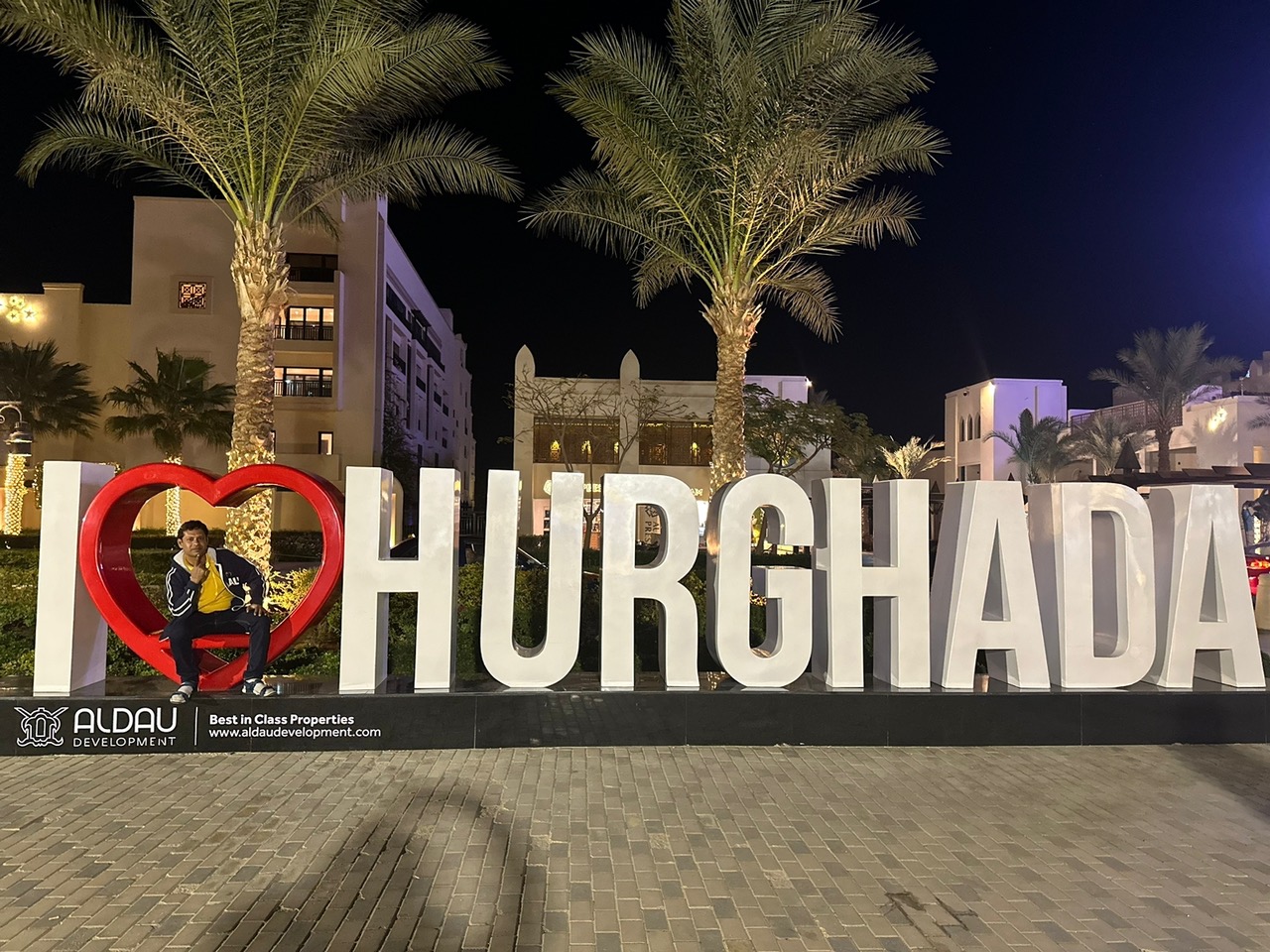 A traveller posing beside an illuminated Hurghada sign at night